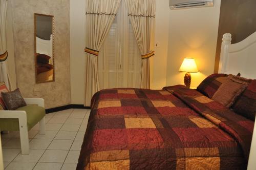 a bedroom with a bed and a chair and a lamp at Marchabell by the Sea E22 in Ocho Rios