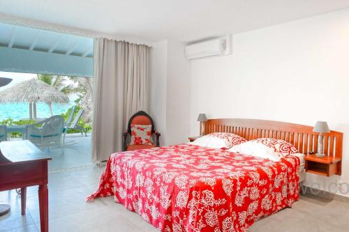 a bedroom with a bed with a red and white blanket at Villa Liléa in Saint-François