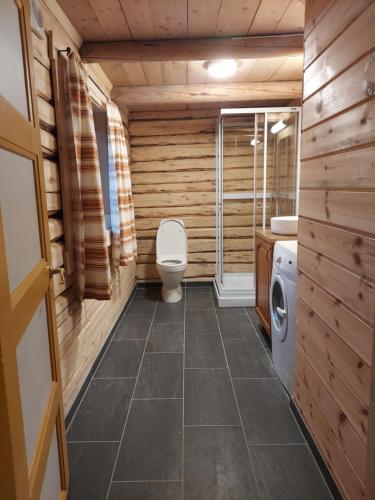 a bathroom with a toilet and a washing machine at Villmarksgård tømmerstue in Hattfjelldal