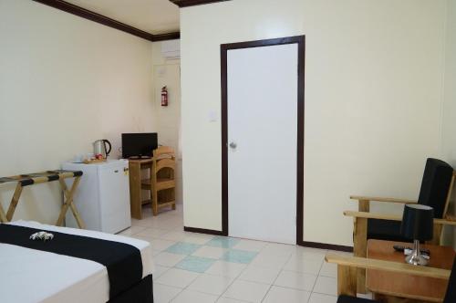 a room with a bed and a refrigerator and a door at Moatoga Hotel in Apia
