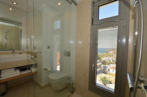 a bathroom with a toilet and a sink and a window at Ino Hotel & Suites in Samos