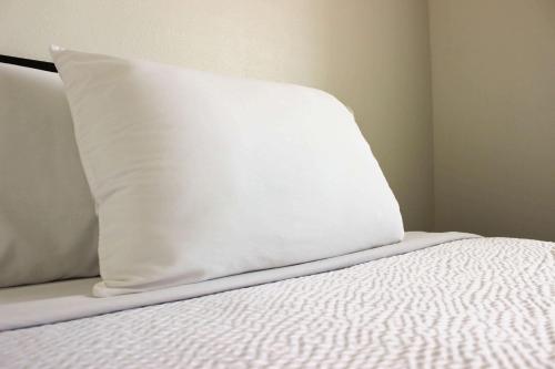 a white pillow sitting on top of a bed at Motel 6 Rexburg, ID in Rexburg