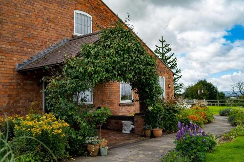 a brick house with a bunch of plants around it at Higher Farm in Malpas