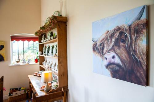 a painting of a cow hanging on a wall at Higher Farm in Malpas