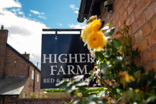 a sign on a brick wall with a yellow flower at Higher Farm in Malpas