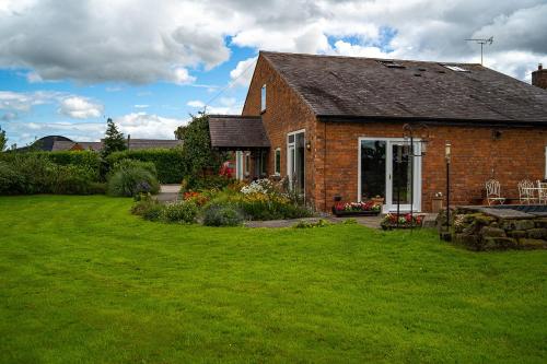 a brick house with a green lawn in front of it at Higher Farm in Malpas
