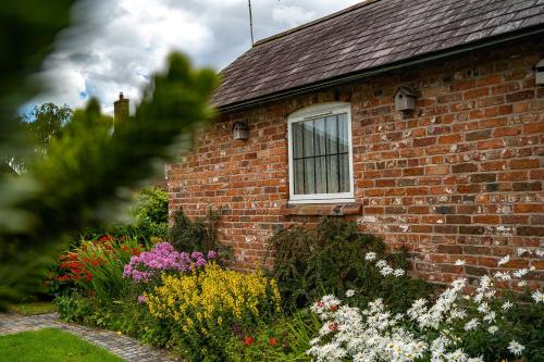 a brick house with a window and a bunch of flowers at Higher Farm in Malpas