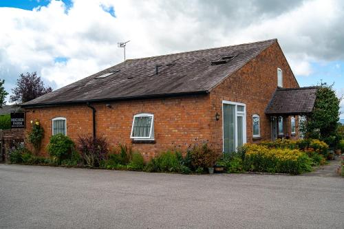a red brick building with a black roof at Higher Farm in Malpas