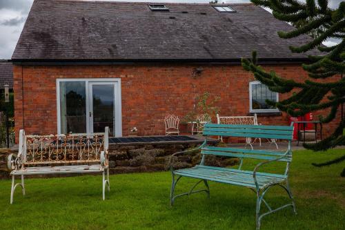two benches sitting in the grass in front of a house at Higher Farm in Malpas