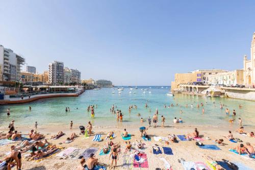 Un grupo de personas en una playa en el agua. en Brand new apartment in Sliema 2 min by the sea, en Sliema