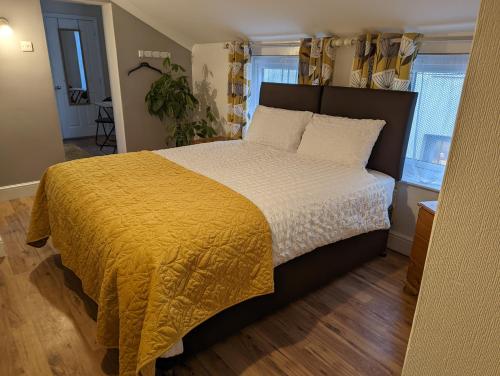 洛斯托夫特的住宿－Gull Wing Guesthouse，一间卧室配有一张带黄色毯子的大床