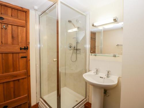 a bathroom with a glass shower and a sink at Stable End in Pembridge