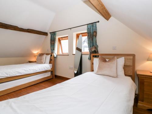 two beds in a room with two windows at The Hop Kiln in Pembridge