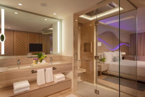 a bathroom with a sink and a shower and a bed at Breathless Cancun Soul Resort & Spa - Adults Only - All Inclusive in Cancún