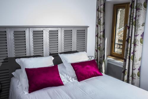 a bedroom with a white bed with two purple pillows at La Tissandière in Lalbenque