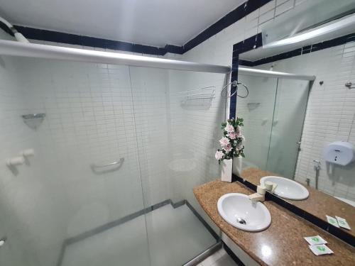 a bathroom with two sinks and a glass shower at Lindo Estúdio vista mar com cama king in João Pessoa