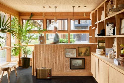 丹尼斯的住宿－Bluebird Dennisport，一间设有木镶板的房间,一个女人站在窗户旁