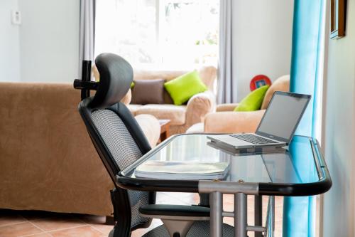 a glass table with a laptop on a chair in a living room at Villa Lazy Daze in Jolly Harbour