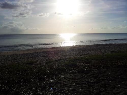 a beach with the sun rising over the ocean at Villa Lazy Daze in Jolly Harbour