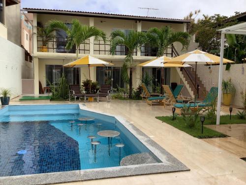 uma piscina com mesas e guarda-sóis em frente a um edifício em Pousada Villa Encantada LGBTQIAPlus em Salvador