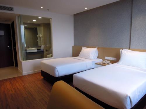 a hotel room with two beds and a mirror at Hotel Excelsior Ipoh in Ipoh