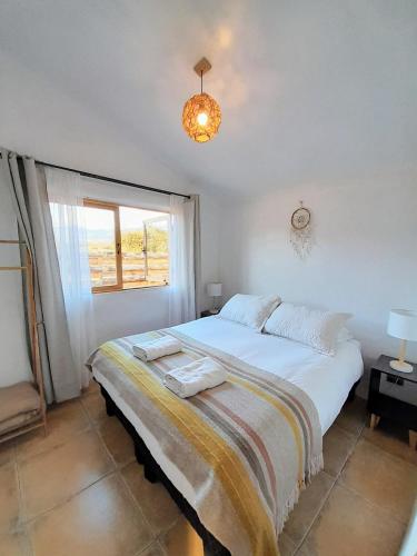 a bedroom with a large white bed and a window at Eco Parcela La Chacra in Catapilco