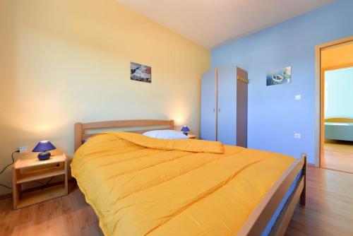 a bedroom with a bed with a yellow bedspread at Paklina apartments in Starigrad-Paklenica