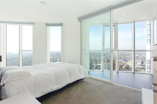 ein weißes Schlafzimmer mit einem großen Bett und großen Fenstern in der Unterkunft luxurious 2 bed apartment central London in London