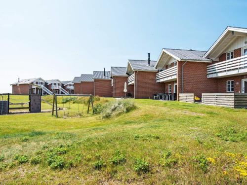 a row of houses with a grassy field in front at 6 person holiday home in R m in Rømø Kirkeby