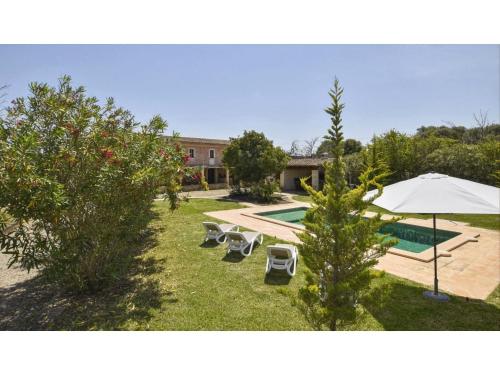 un patio trasero con piscina, sombrilla y sillas en Belvilla by OYO Cadernera, en Búger
