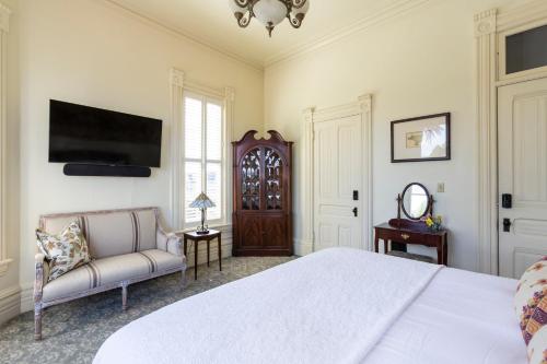 a bedroom with a bed and a couch and a tv at Pinc Lady Mansion in Eureka