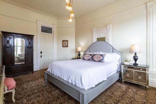 a bedroom with a large bed and a chair at Pinc Lady Mansion in Eureka