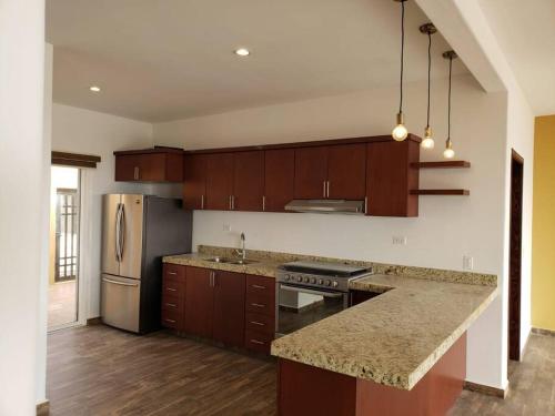 a kitchen with wooden cabinets and a granite counter top at Casa Relax en La Mision, gran vista, chimenea in Rosarito