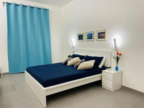 a bedroom with a bed with a blue curtain at Sicilian Rooms in Avola