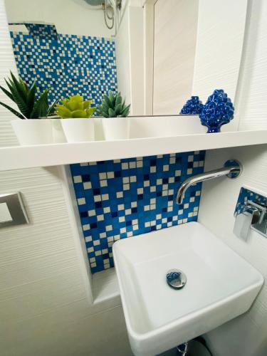 a bathroom with a sink and blue and white tiles at Sicilian Rooms in Avola