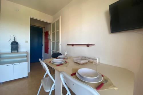 une cuisine avec une table avec des assiettes blanches dessus dans l'établissement 23m paisible avec balcon près de la plage !, à Cabourg