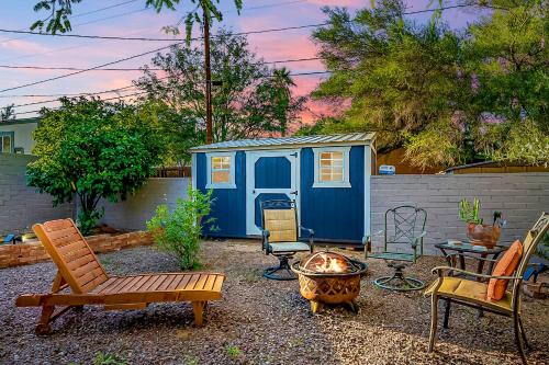 ツーソンにあるPeaceful Tucson Tiny House Getaway with Backyardの青い小屋と椅子と火炉のある裏庭