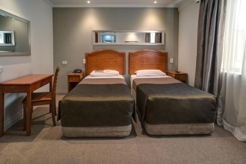 a bedroom with two beds and a table and a desk at Great Southern Hotel Sydney in Sydney