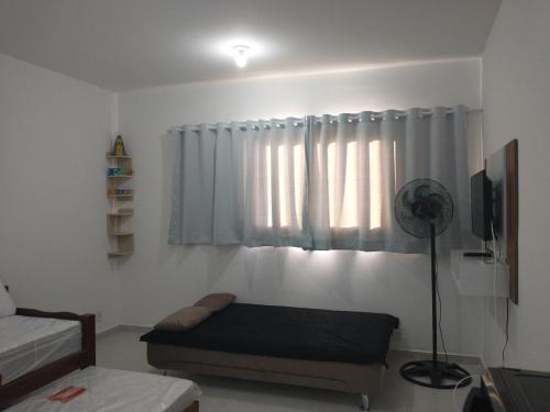 ein Wohnzimmer mit einem Bett und einem Fenster in der Unterkunft Kitnet pertinho da Canção Nova in Cachoeira Paulista