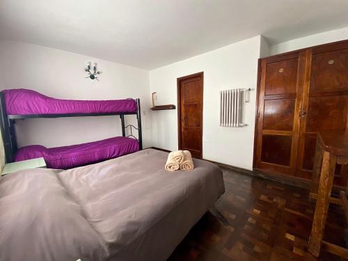sypialnia z dużym łóżkiem z fioletową pościelą w obiekcie Hostel Planeta Cumbrecita w mieście La Cumbrecita