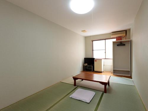 a living room with a table and a window at Tabist Izumi Yusen Shukuhaku Center in Izumi