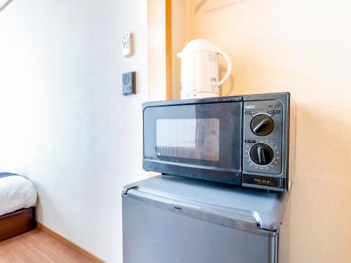 a microwave sitting on top of a refrigerator at Tabist Tatsumi Business Hotel Matsusaka in Matsuzaka
