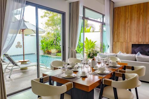 a dining room with a table and chairs and a couch at Shambhala grand villa by Cozy Lake in Bang Tao Beach
