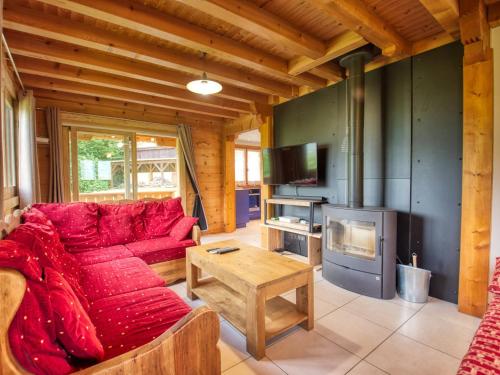 - un salon avec un canapé rouge et une cheminée dans l'établissement Chalet paisible à Morillon avec jacuzzi et proche des pistes skiables - FR-1-642-66, à Morillon