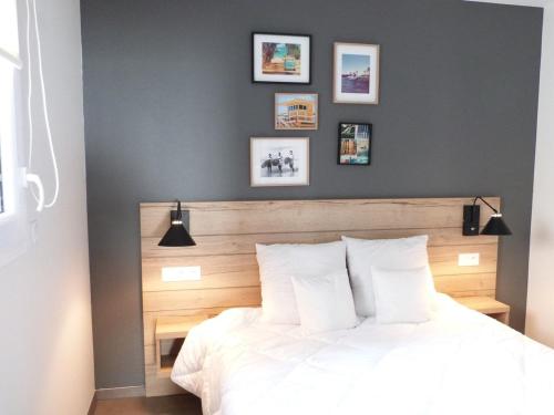 a bedroom with a white bed and some pictures on the wall at Appartement bord de mer avec accès plage, piscine, jacuzzi, 1 chambre, animaux admis, parking inclus - FR-1-194-253 in La Tranche-sur-Mer