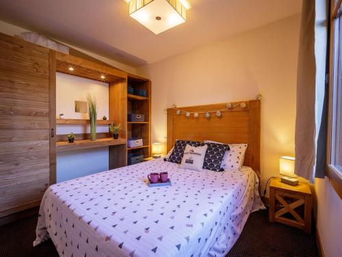 une chambre avec un grand lit avec une tête de lit en bois dans l'établissement Appartement Prestige au Centre-ville avec Piscine, Sauna et Parking à Saint-Lary-Soulan - FR-1-296-417, à Saint-Lary-Soulan