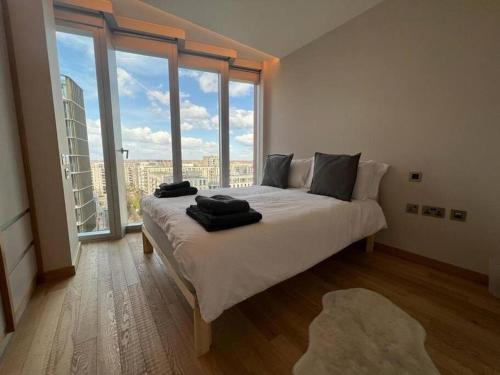 sypialnia z dużym łóżkiem i dużym oknem w obiekcie Manhattan Loft Gardens, Stratford E20 w Londynie