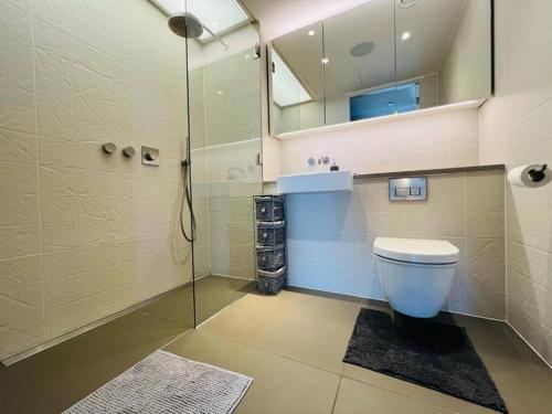a bathroom with a toilet and a glass shower at Manhattan Loft Gardens, Stratford E20 in London