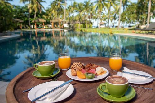 a table with breakfast foods and drinks next to a pool at Lomani Island Resort & Spa in Malolo Lailai