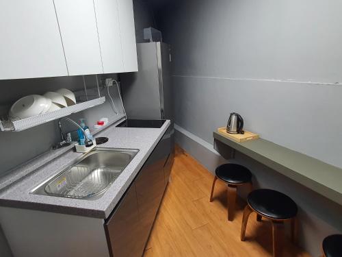 a small kitchen with a sink and two stools at Daljee Guesthouse in Seoul
